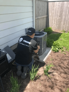 A Nortek technician working on an AC condenser—call Nortek at (630) 548-1500 to schedule service.